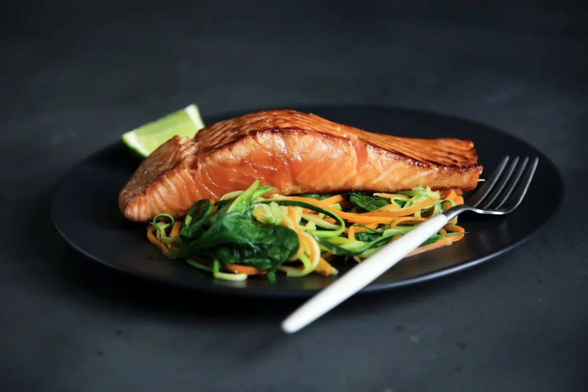 Fresh broiled salmon fillets glistening with bubbly caramelized honey mustard glaze, fresh lemon slices, and chopped parsley on a cast iron sizzle platter