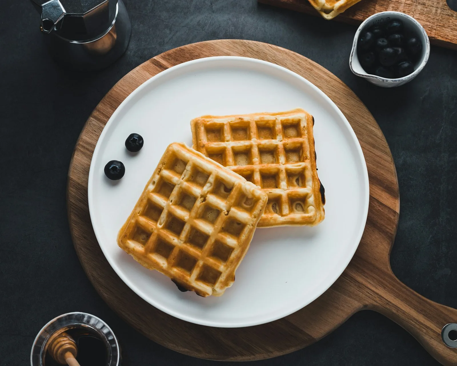 Crisp golden Belgian waffles with deep pockets dusted with powdered sugar, fresh berries and maple syrup