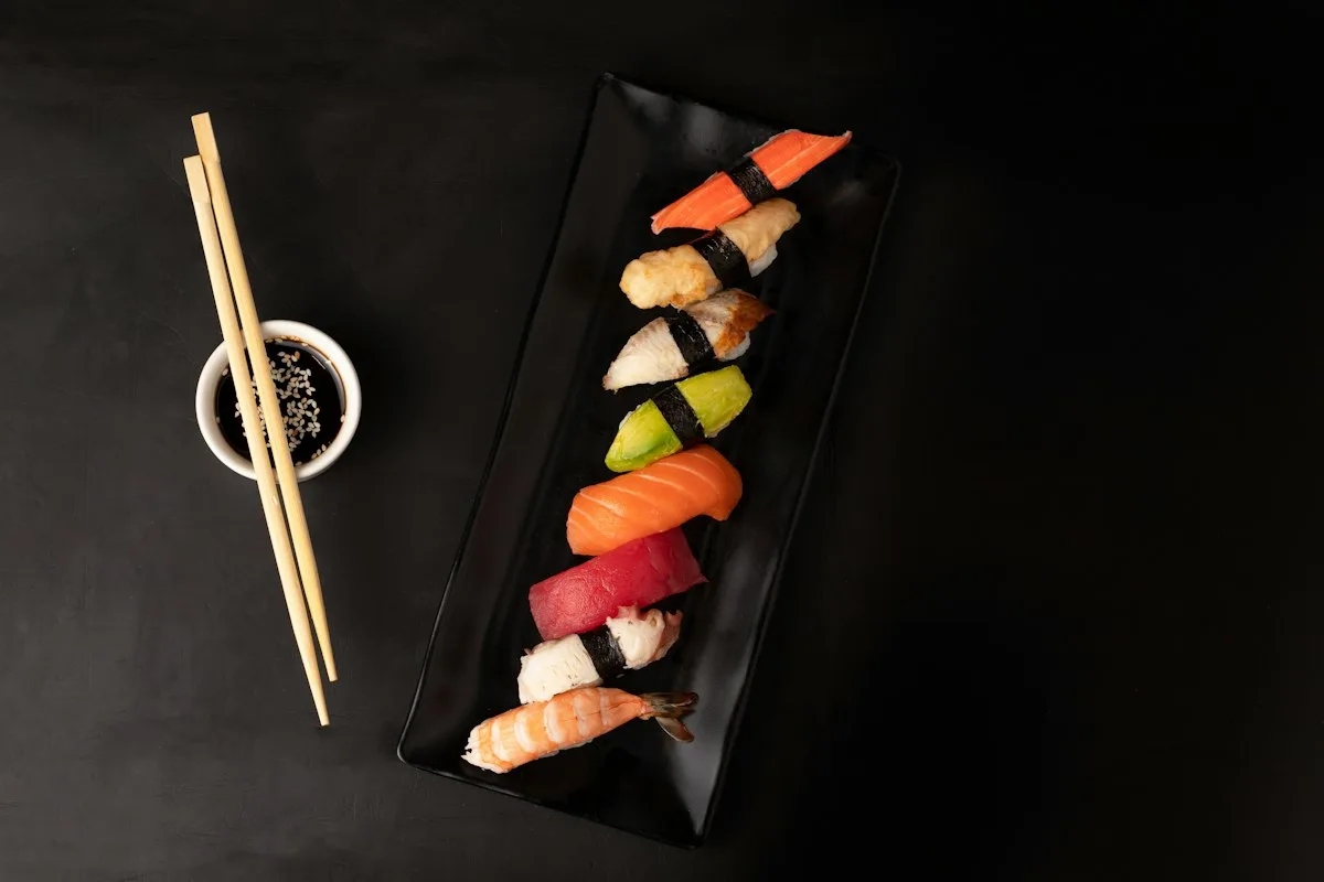 Golden pan-fried crispy sushi rice squares topped with spicy fresh salmon tartar, jalapeño slice, and sriracha mayo drizzle on a slate platter
