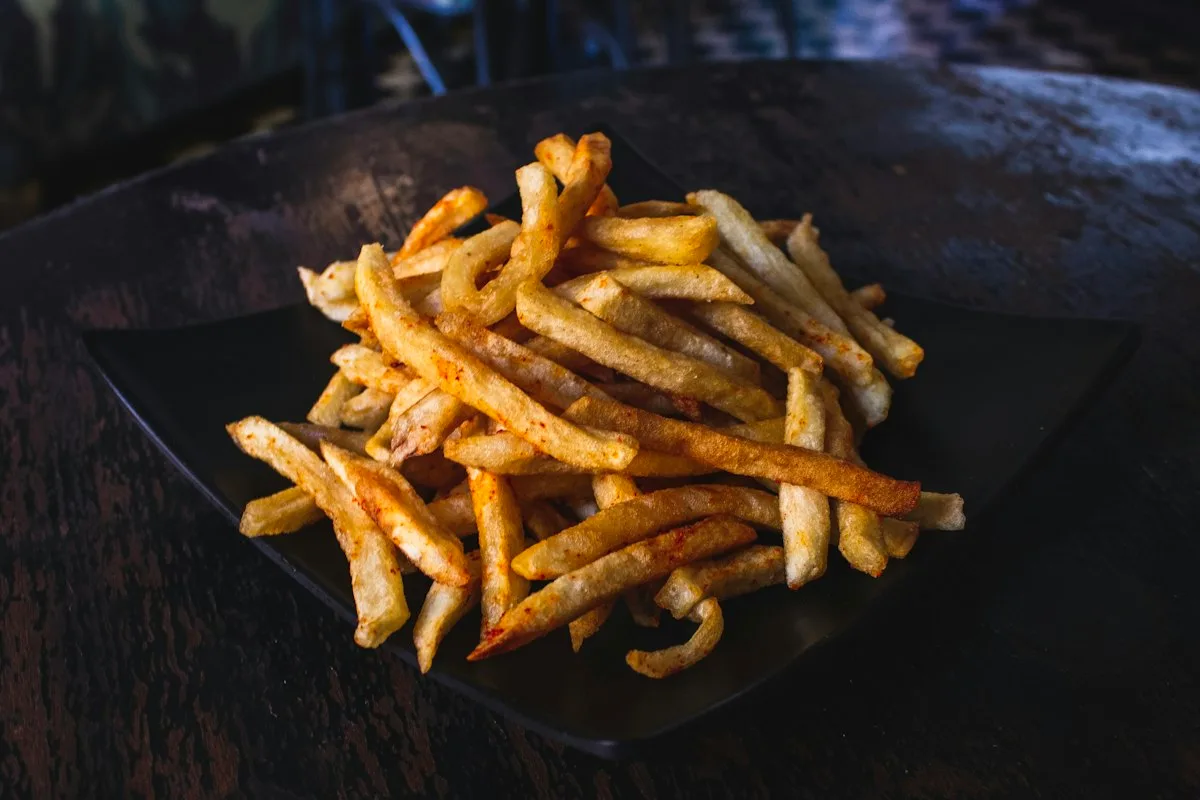 Stack of golden crispy baked zucchini fries coated in parmesan panko crust served in a bowl with garlic lemon herb dip
